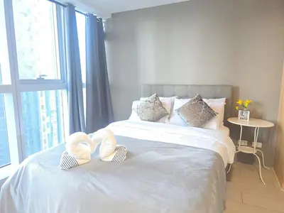 a bed with two towels on it with a window at Uptown Parksuites BGC Cosy Hotel Vibe Flat near St Lukes, Uptown Mall, Mitsukoshi and Grand Hyatt in Manila