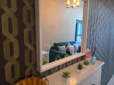 a living room with a mirror and a green couch at Uptown Parksuites BGC Cosy Hotel Vibe Flat near St Lukes, Uptown Mall, Mitsukoshi and Grand Hyatt in Manila