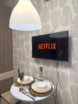 a tv on a wall above a table with plates and glasses at CozyCalmStaycation in Manila