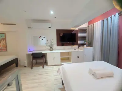 a bedroom with a bed and a desk with a television at L1 Twin Bed Staycation in BGC in Manila