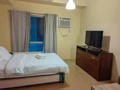 a bedroom with a bed and a flat screen tv at unit 130 Studio Type Avida Cityflex BGC in Manila