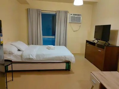 a bedroom with a bed with a television and a dresser at unit 130 Studio Type Avida Cityflex BGC in Manila