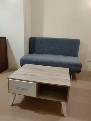 a blue couch sitting in a room with a coffee table at unit 130 Studio Type Avida Cityflex BGC in Manila
