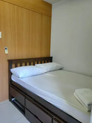 a bed with a wooden headboard and white sheets at Apartment Shell Residences near MOA in Manila