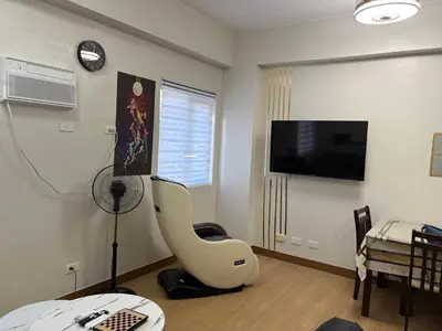 a living room with a white chair and a television at G-VibeZzz Staycation in Trece Martires