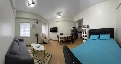 a bedroom with a blue bed and a living room at G-VibeZzz Staycation in Trece Martires
