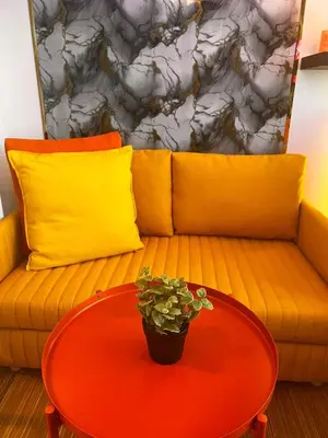 a orange couch with a red table and a yellow pillow at Zhafira Retreat in Manila