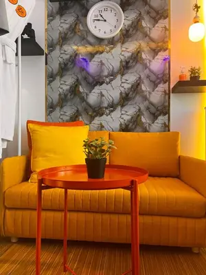 a yellow couch with a table and a clock at Zhafira Retreat in Manila