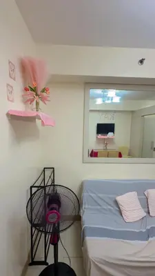 a bedroom with a bed and a mirror and a table at 10th Floor Staycation in Manila