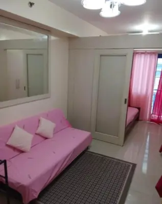 a pink couch in a room with a mirror at 10th Floor Staycation in Manila