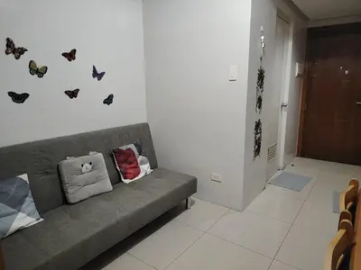 a couch in a room with butterflies on the wall at AteAbyPlace830 in Manila