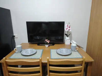 a wooden table with two chairs and a television at AteAbyPlace830 in Manila