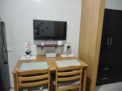 a wooden table with two chairs and a television on top at AteAbyPlace830 in Manila