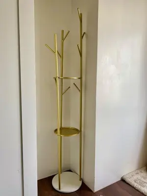 a gold book shelf in a corner of a room at Sunrise Haven in Makati AIR Residences in Manila