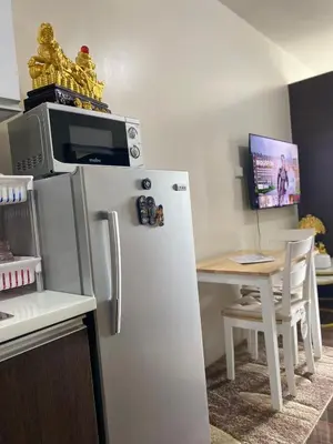a kitchen with a refrigerator and a table with a microwave at Sunrise Haven in Makati AIR Residences in Manila