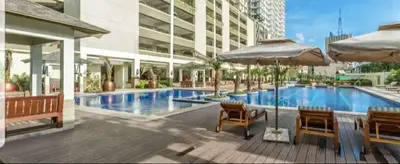a swimming pool with chairs and umbrellas next to a building at 1BR LaVerti Cloud Nine Suite Family Affordable Staycation in Manila