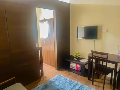 a room with a table and a television and a door at Affordable Condo in Makati Air Residences in Manila