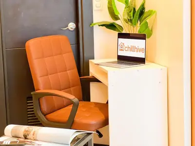 an orange chair sitting next to a desk with a laptop at Prime BGC 1BR Near Grand Hyatt & Malls #upt215e in Manila