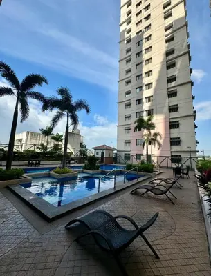 a swimming pool with palm trees and a building at Family Comfort Zone Staycation at Greenhills in Manila