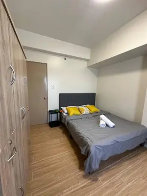 a bedroom with a bed with yellow pillows at 1Bedroom, living room w balcony ADHI staycation in Biñan