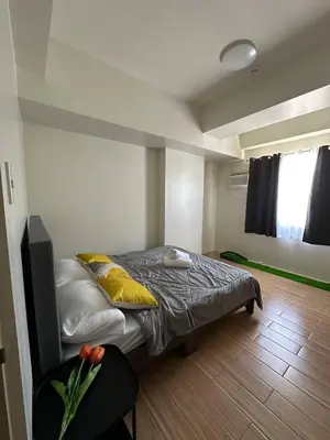 a bedroom with a bed with yellow pillows and a window at 1Bedroom, living room w balcony ADHI staycation in Biñan