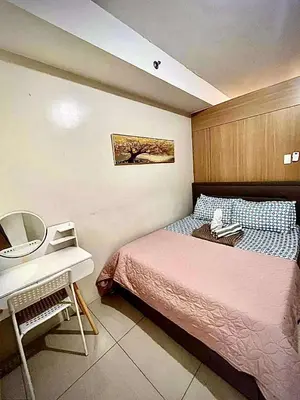a small bedroom with a bed and a desk at Staycation Near Mall of Asia in Manila