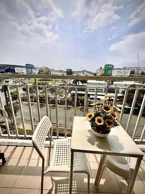 a table and chairs on a balcony with a bowl of flowers at Staycation Near Mall of Asia in Manila