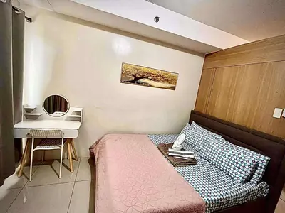 a small bedroom with a bed and a desk at Staycation Near Mall of Asia in Manila