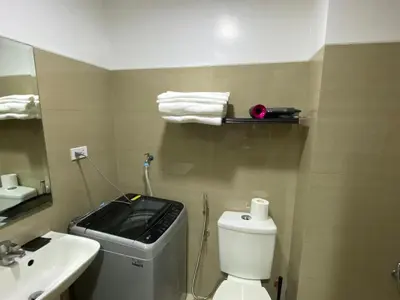 a bathroom with a white toilet and a sink at Shore - Spacious Room with Balcony - 52D in Manila