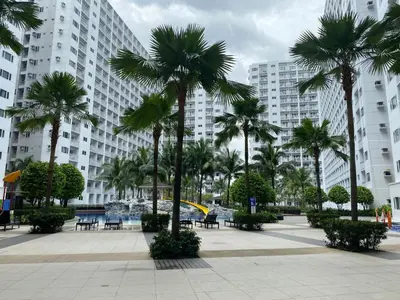 a courtyard with palm trees in front of a building at Shore - Spacious Room with Balcony - 52D in Manila
