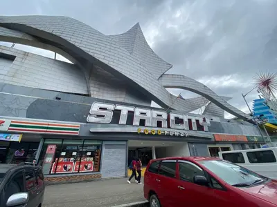 a red car parked in front of a store at Shore - Spacious Room with Balcony - 52D in Manila