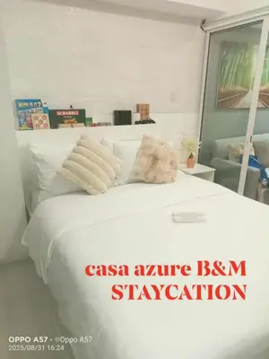 a white bed with a teddy bear laying on it at Casa azure by B&M STAYCATION at Paranque in Manila