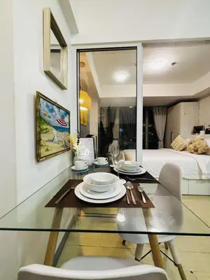 a glass dining room table with two chairs and a bed at Casa azure by B&M STAYCATION at Paranque in Manila