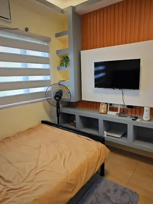 a bedroom with a flat screen tv and a fan at Condo Unit, 2 Beds, Wi-fi, Free Amenities in Manila