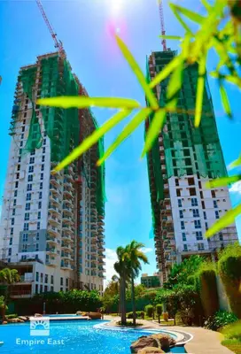 two tall buildings with palm trees in front of a pool at Kasara Pasig Staycation in Manila