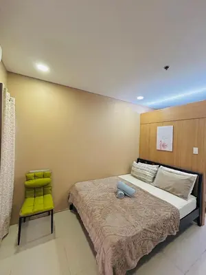 a bedroom with a bed and a yellow chair at Milk and honey condotel in Manila
