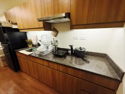 a kitchen counter with a sink and a refrigerator at The Camden Place Family Group Apartment Condo Unit in Manila