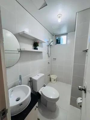 a white bathroom with a toilet and a sink at 2 Bedroom Unit with Queen-sized Beds near NAIA T3 in Manila