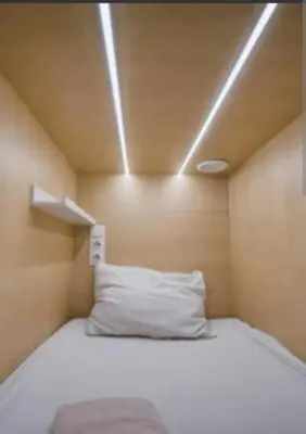 a bed in a small room with a white pillow at Victoria's capsule bed in Manila