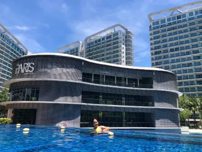 a woman in a swimming pool in front of a building at Azure Luxe Suites in Azure Bicutan Near NAIA and MOA in Manila