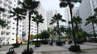 a group of palm trees in a city with tall buildings at 1BR Amenity View Room at Shore Residences, Pasay Near MOA & Airport in Manila