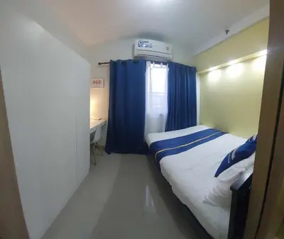 a bedroom with a bed and a window with blue curtains at GB Travelers Rest at Shore 2 Residences in Manila
