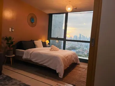 a bedroom with a bed and a large window at Bgc One Uptown Residences in Manila
