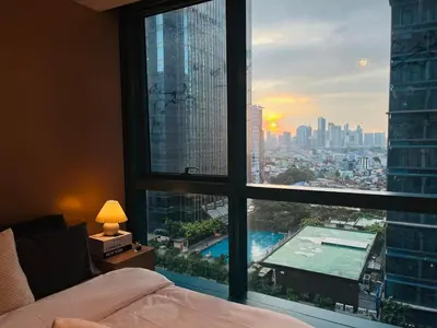 a bedroom with a large window with a view of a city at Bgc One Uptown Residences in Manila