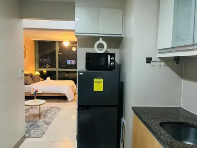 a kitchen with a black refrigerator and a bedroom at Bgc One Uptown Residences in Manila