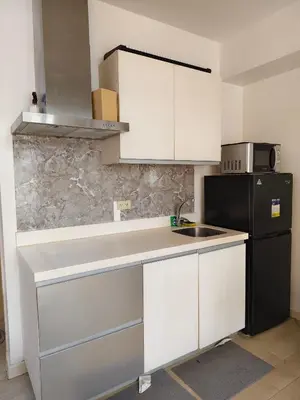 a kitchen with white cabinets and a black refrigerator at MG Labels Property in Manila