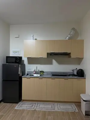 a kitchen with wooden cabinets and a black refrigerator at Paseo Verde at Real in Manila
