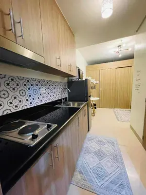 a kitchen with a black counter top and wooden cabinets at Jaiden & Blake Sweet Home in Manila