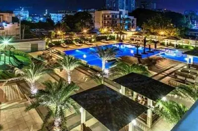 a large pool with palm trees in a city at night at 1BR LaVerti Minalist affordable family staycation in Manila