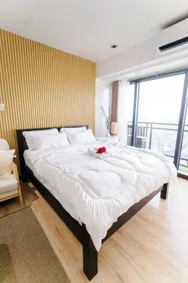 a large white bed with a flower on top of it at Modern Studio with Balcony at Knightsbridge Residences, Poblacion Makati in Manila